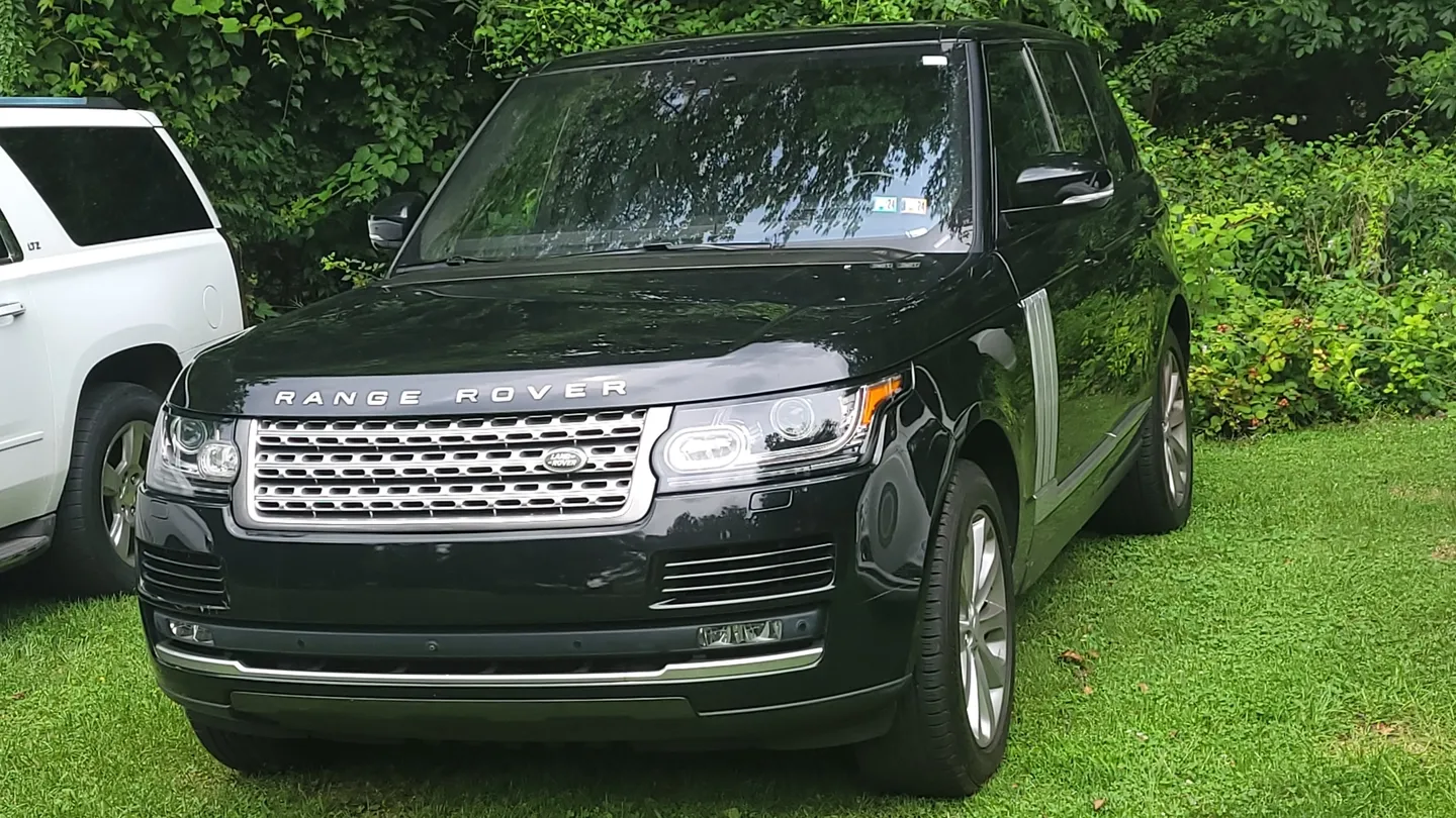 A black range rover parked in the grass.